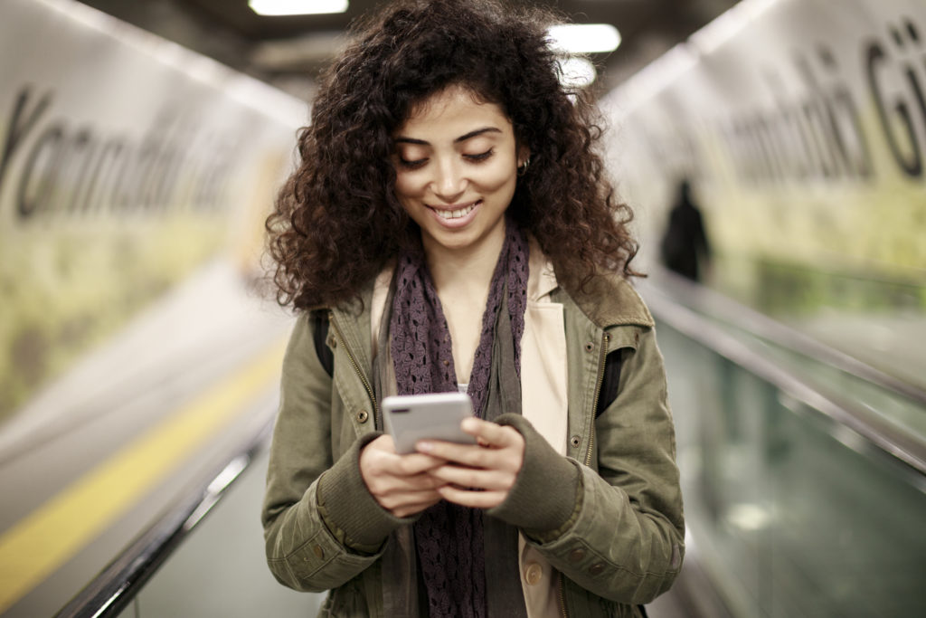 Young woman using mobile phone in the subway station